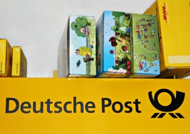 Einige Pakete stehen auf einem sehr großen Paket mit der Aufschrift Deutsche Post. Eins darunter mit DHL. Hier für Versand und sofort lieferbare Onlinebestellungen.