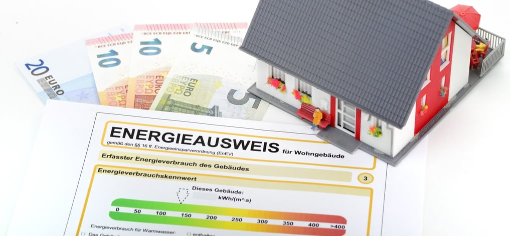 Ein Energieausweis für Nichtwohngebäude und ein Modell eines Gebäudes.